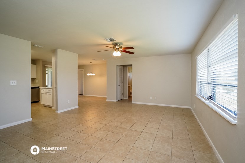 an empty living room with a ceiling fan and a large window