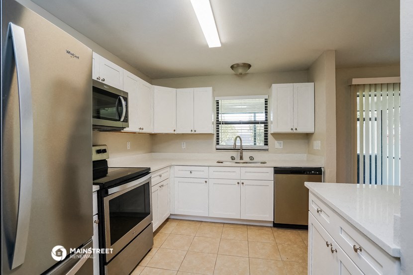 a kitchen with white cabinets and a sink and a refrigerator