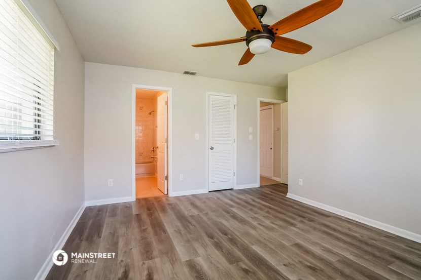 a living room with a ceiling fan and a door to a bathroom