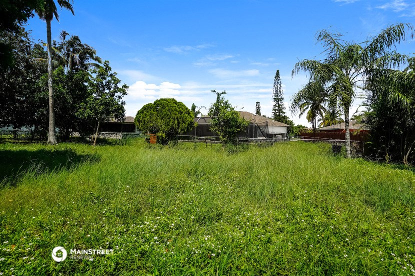 a large field of grass with a house in the background