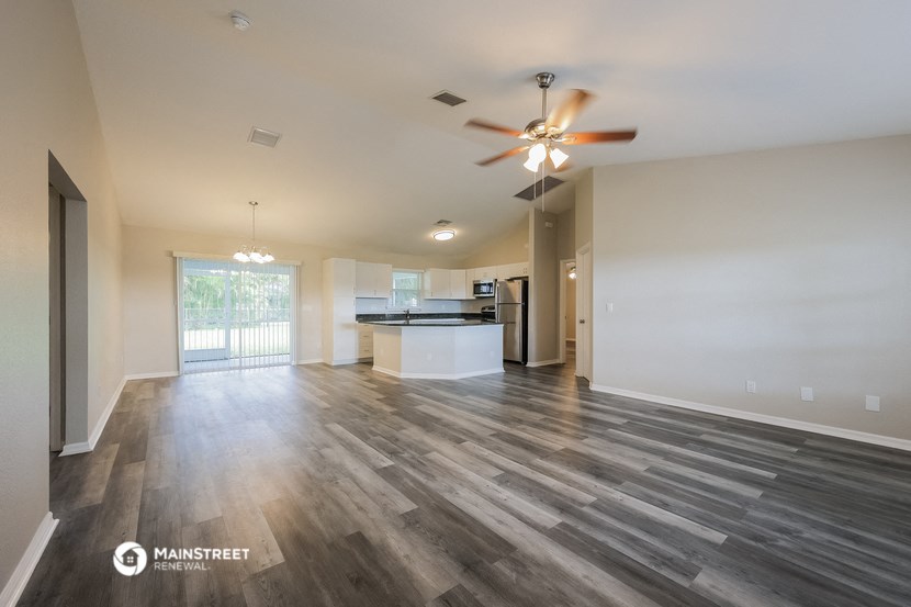 the living room and kitchen of an empty house with a ceiling fan