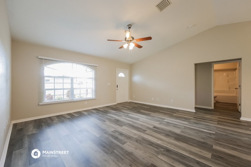 an empty living room with a ceiling fan and a window