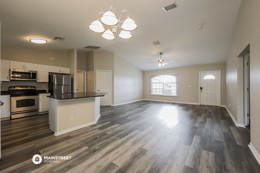 the living room and kitchen of an apartment with wood flooring
