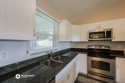 a kitchen with white cabinets and granite counter tops and a sink