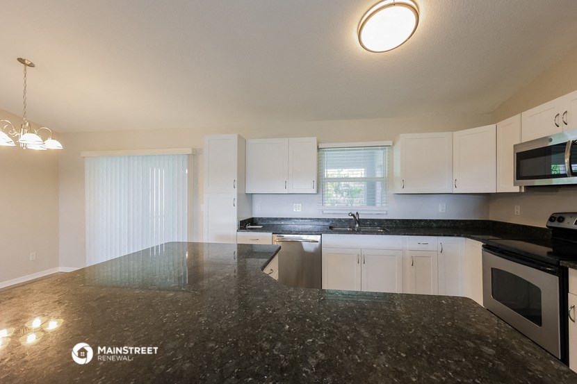 a kitchen with white cabinets and black counter tops and a black marble counter top