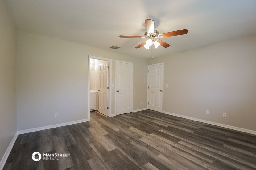the spacious living room with wood flooring and a ceiling fan