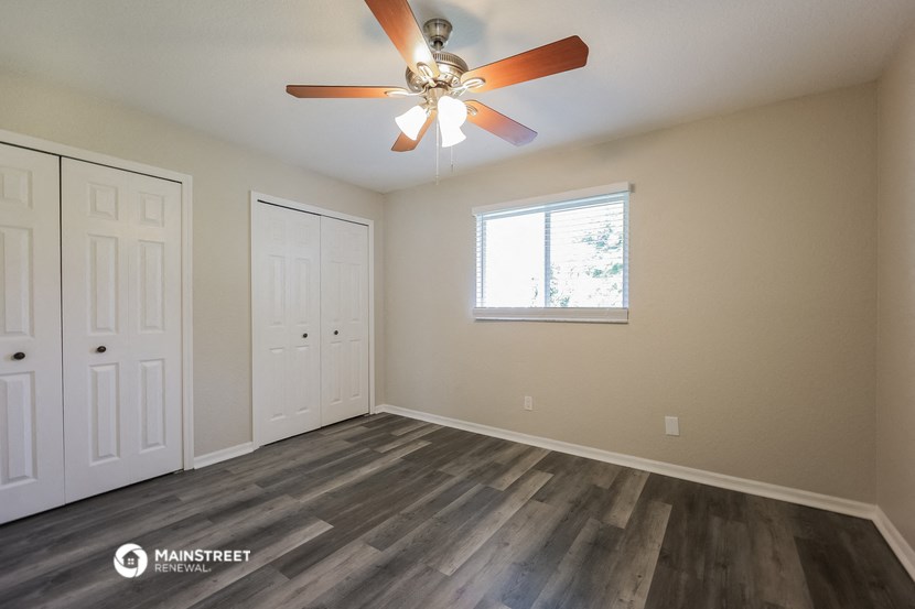 the spacious living room with ceiling fan and closet