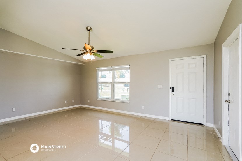 an empty living room with a ceiling fan and a white door