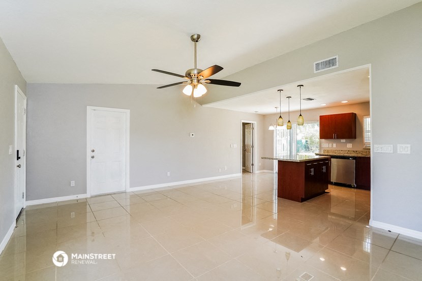 an empty living room and kitchen with a ceiling fan