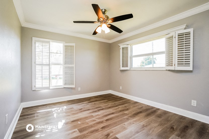 an empty living room with a ceiling fan and windows