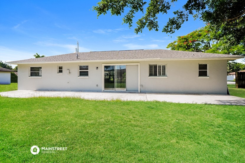 a white house with a green lawn and a driveway
