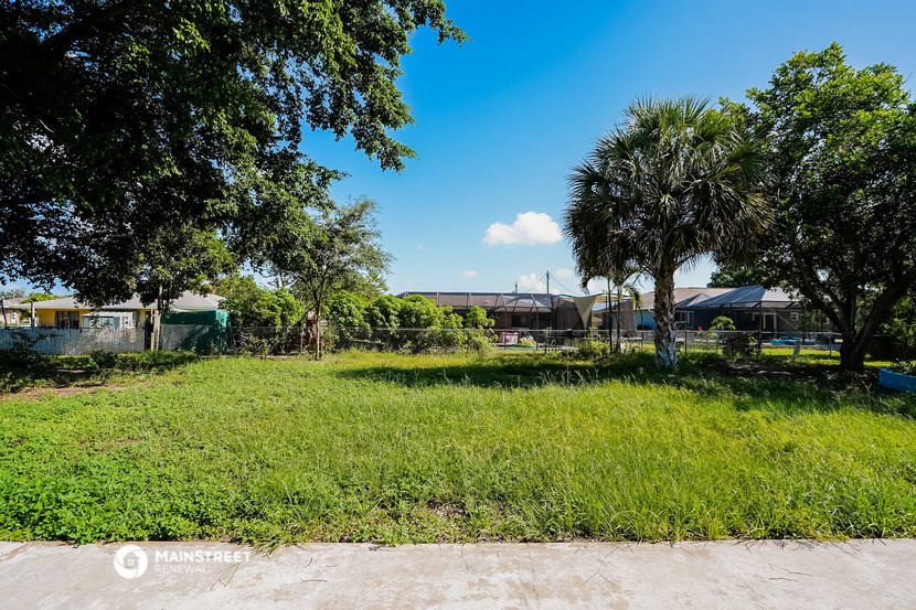 a yard with palm trees and a house in the background