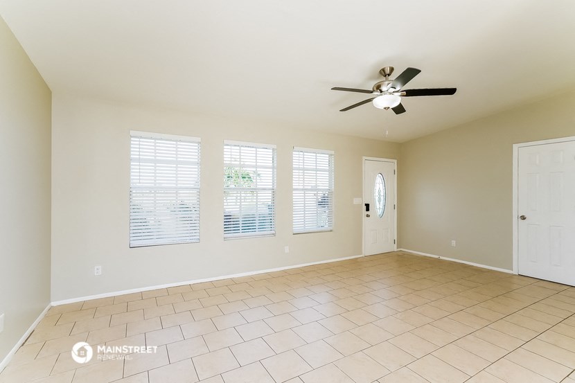 an empty living room with a ceiling fan and windows