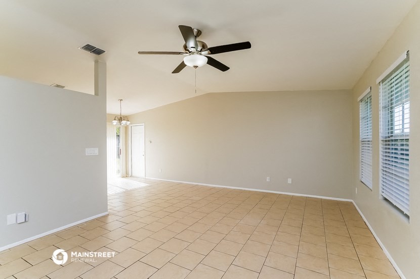 an empty living room with a ceiling fan and a tiled floor