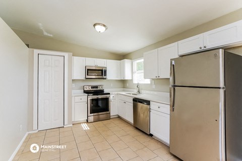 a white kitchen with stainless steel appliances and white cabinets