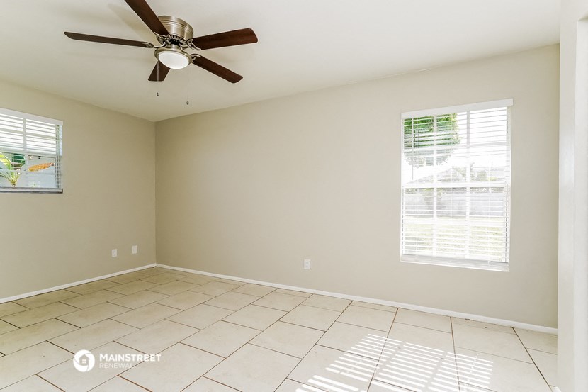 an empty living room with a ceiling fan and a tiled floor
