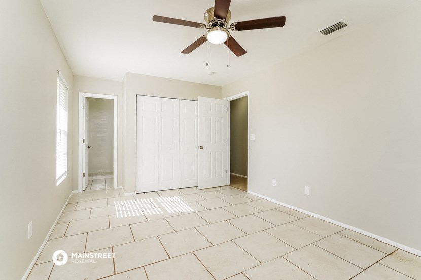 an empty living room with a ceiling fan and tiled floors