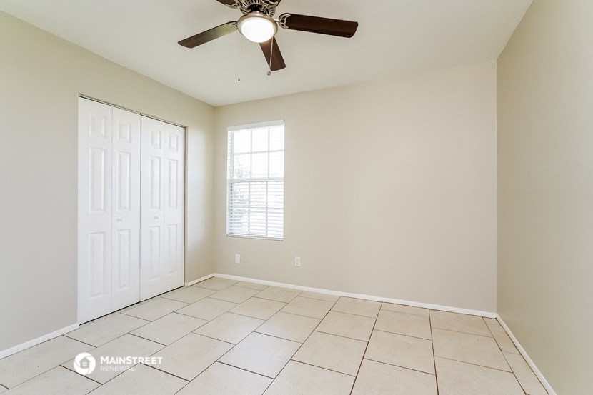 an empty living room with a ceiling fan and tiled floors
