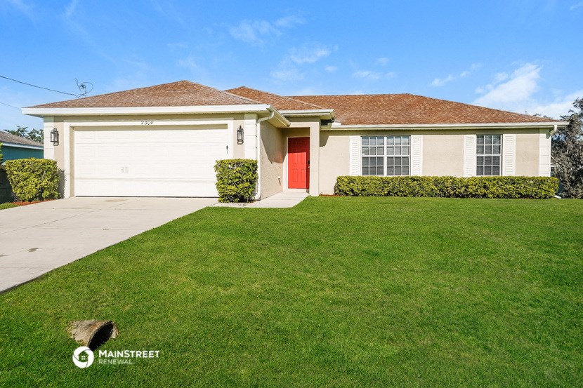 a white house with a red door and a lawn