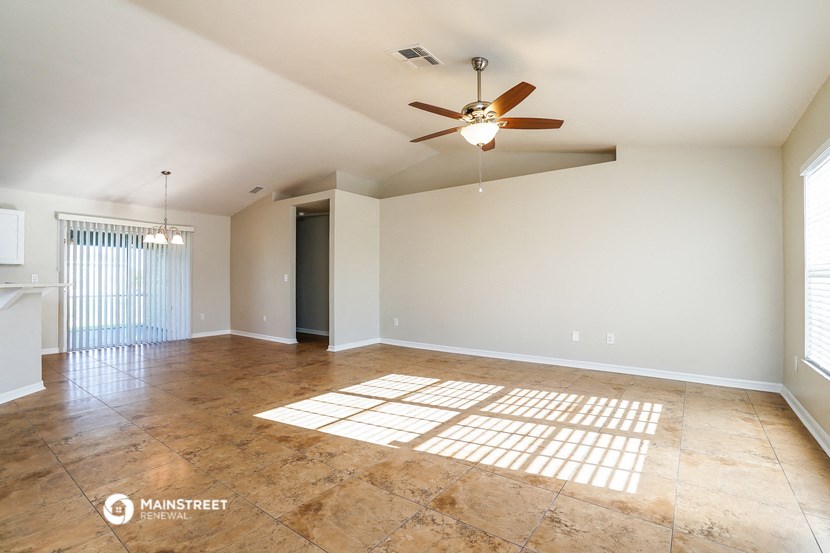 the spacious living room with tile floors and a ceiling fan