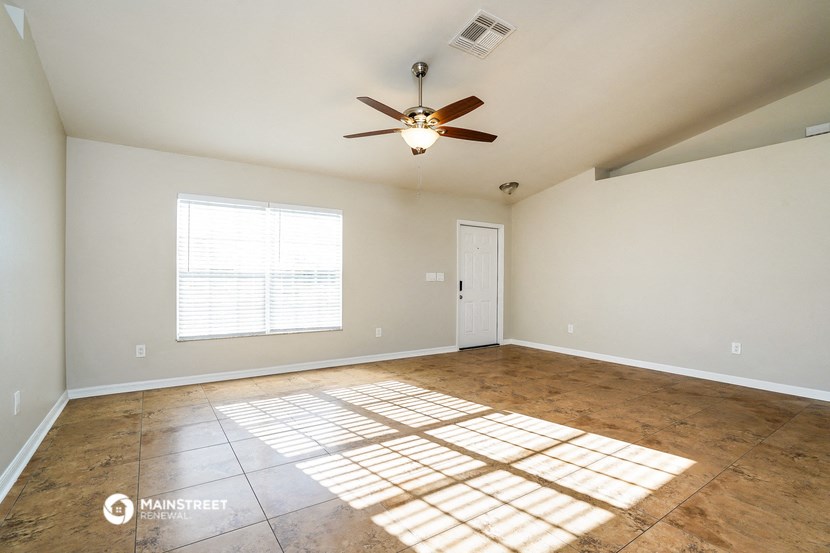 an empty living room with a ceiling fan and a window