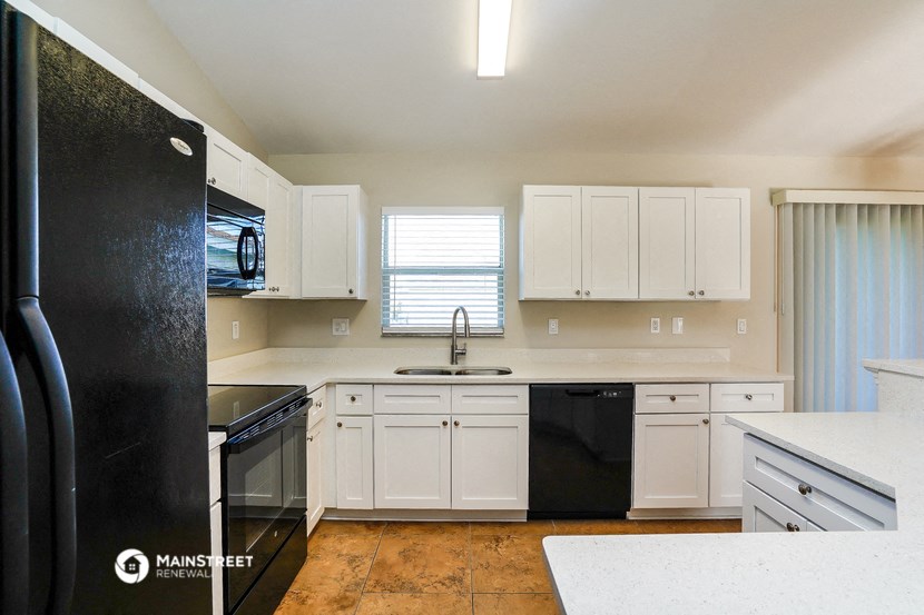 a kitchen with white cabinets and black appliances