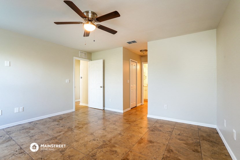 the spacious living room with tile flooring and a ceiling fan