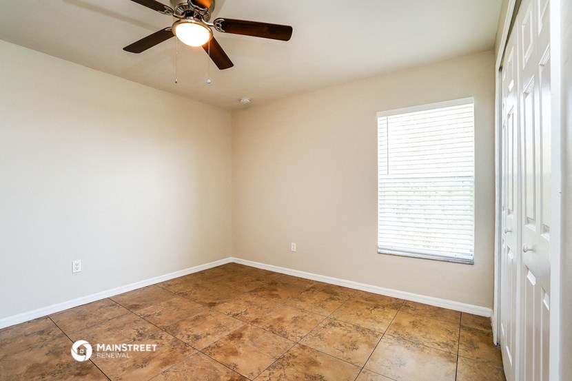 an empty room with a ceiling fan and a window