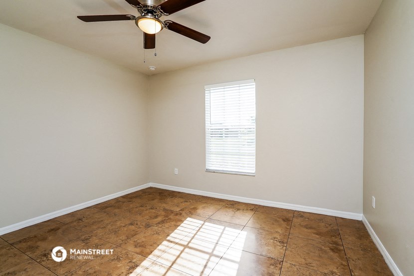 the spacious living room with wood floors and a ceiling fan