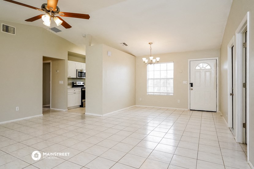 an empty kitchen and living room with a ceiling fan
