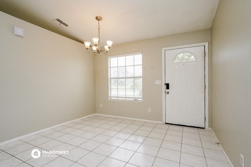 an empty living room with a white tile floor and a white door