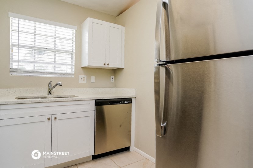 a kitchen with white cabinets and a stainless steel refrigerator