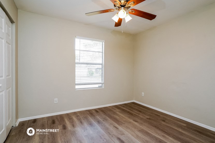 a bedroom with a ceiling fan and wood floors