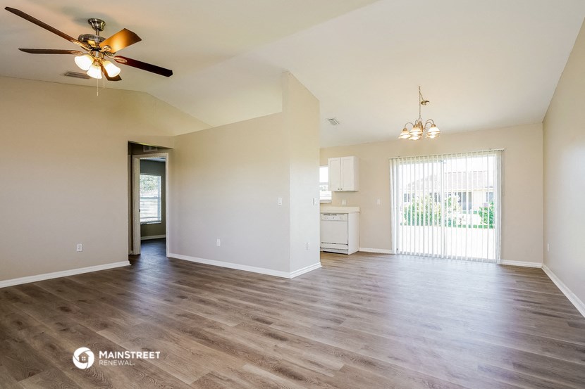 the living room and kitchen of an empty house with a ceiling fan