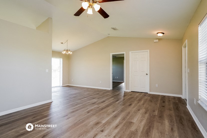 the spacious living room with wood flooring and ceiling fan