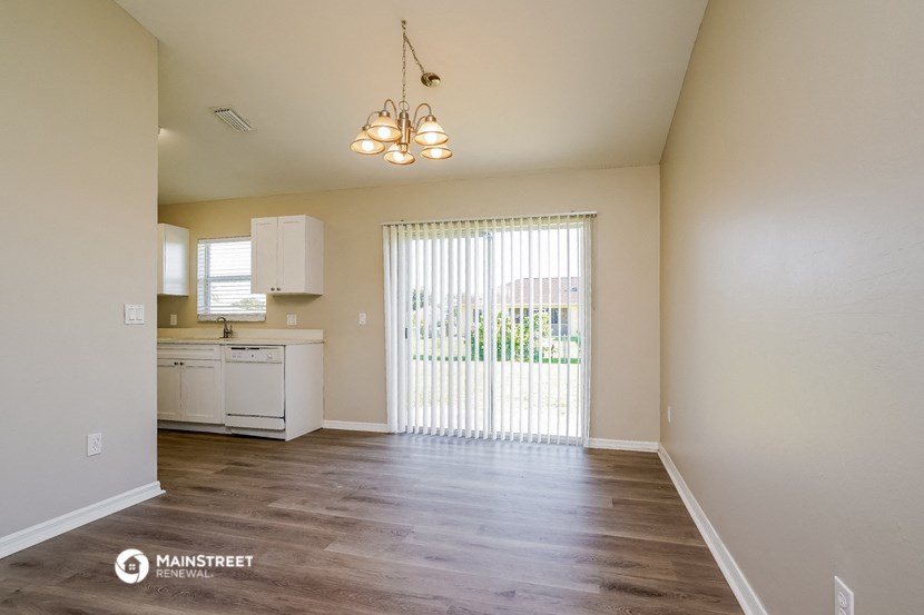a spacious living room with a large window and a kitchen