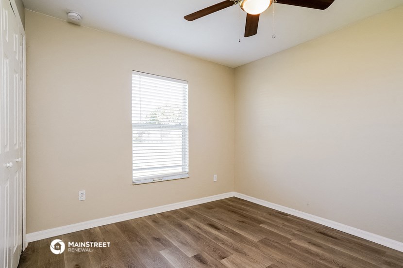 the spacious living room with hardwood floors and a ceiling fan