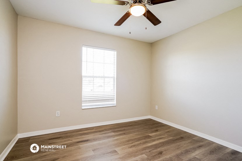 the spacious living room with hardwood floors and a ceiling fan