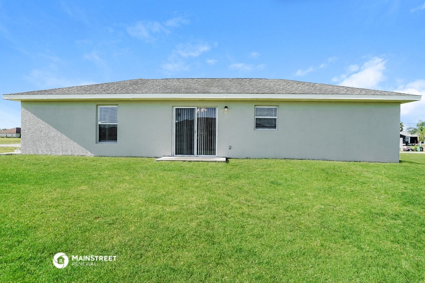 a small white house with a grassy yard in front of it