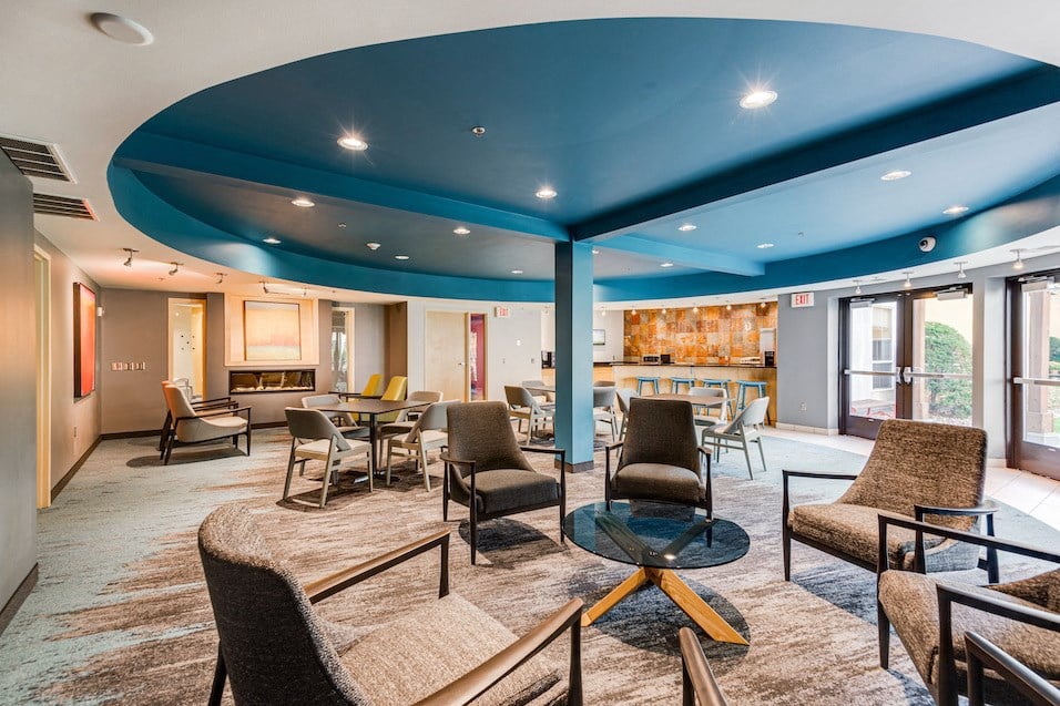 a lobby with chairs and tables and a blue ceiling