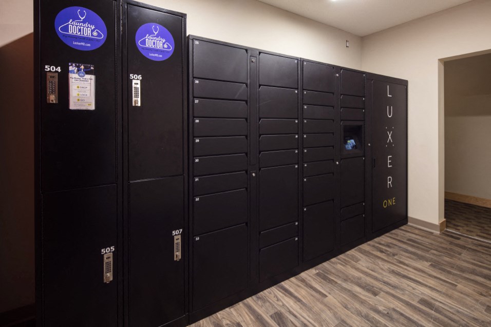 a row of black lockers in a room with a door to a locker room