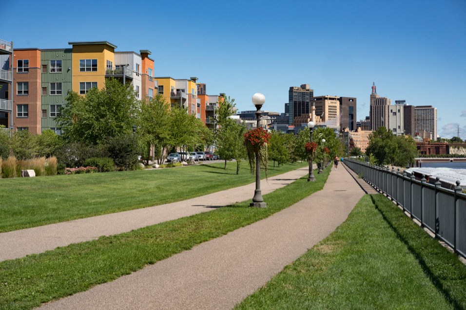 a sidewalk running through a park with the city in the background