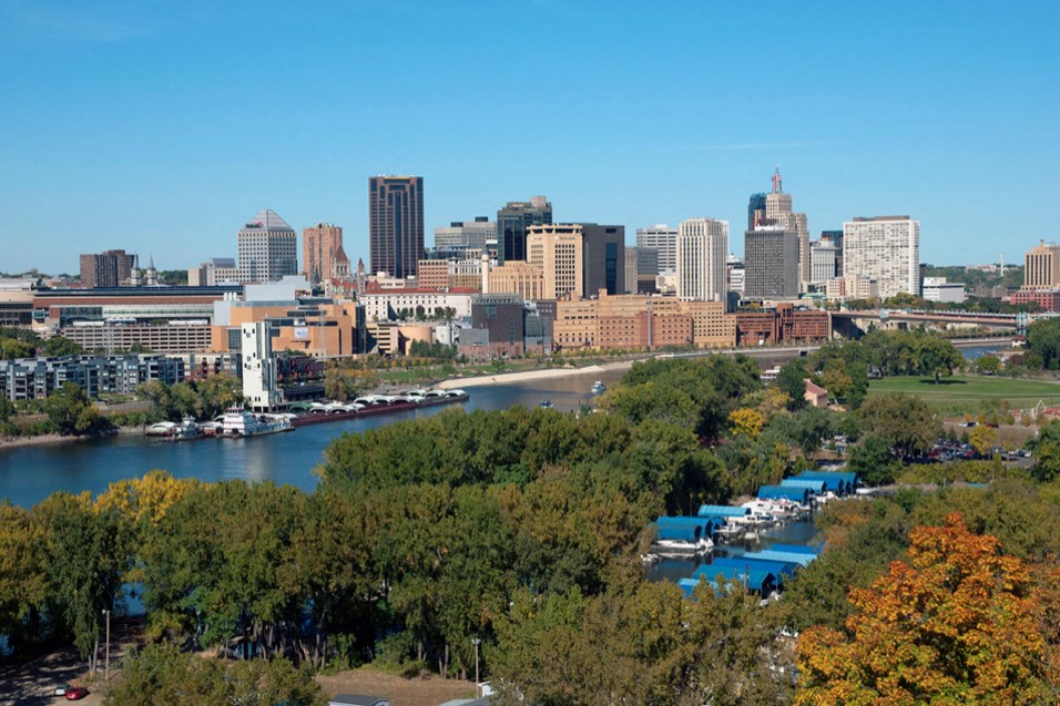 a view of the city from a hill above a river and trees