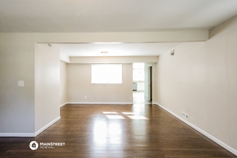 an empty living room with wood floors and white walls