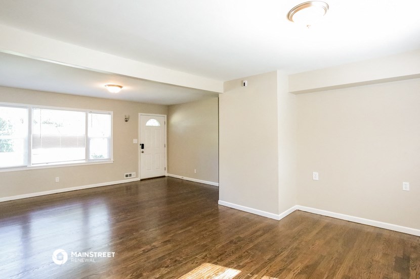 the spacious living room with hardwood flooring and a large window