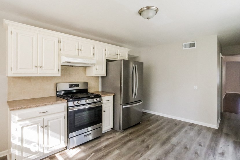 a renovated kitchen with white cabinets and stainless steel appliances