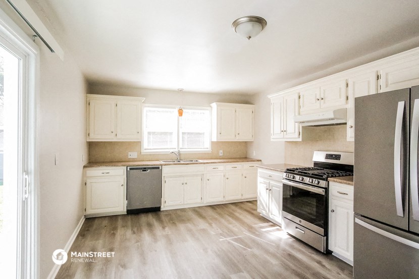 an empty kitchen with white cabinets and stainless steel appliances