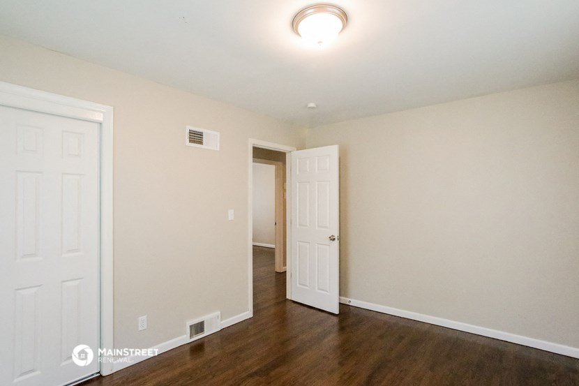 a living room with wood floors and white walls and a white door