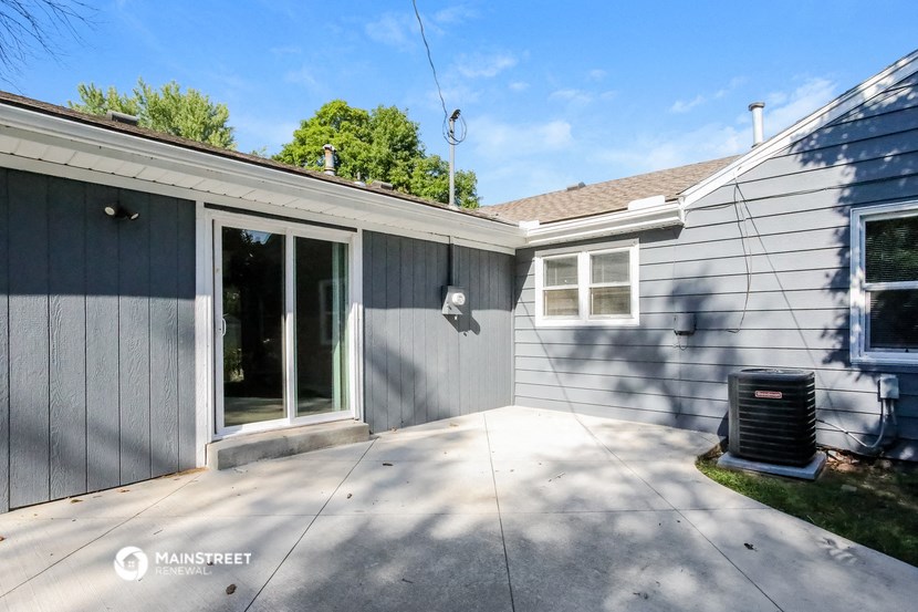a gray house with a backdoor and a patio