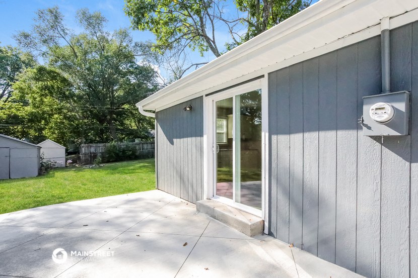 the side of a house with a patio and a backdoor